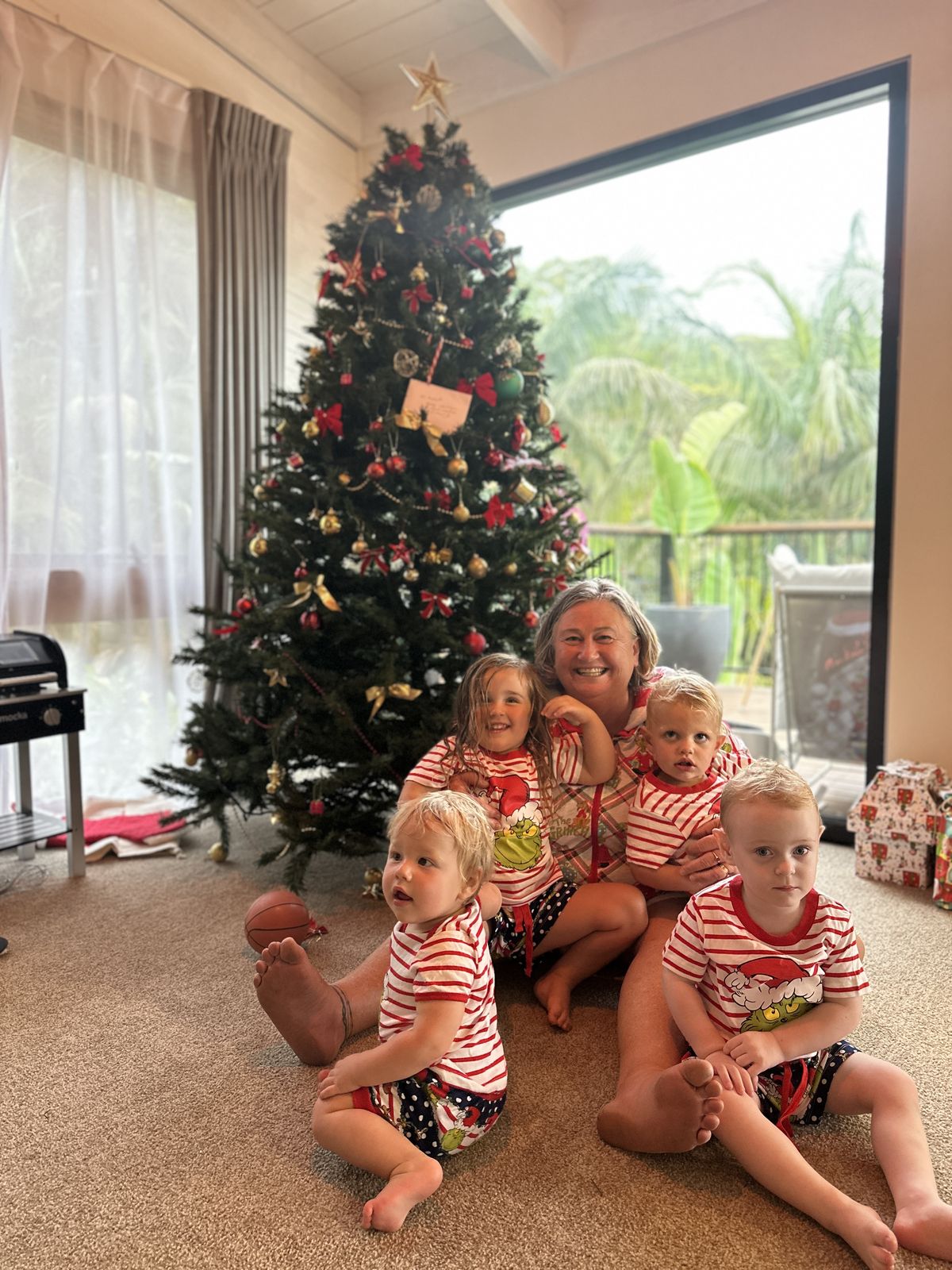 Julie by the Christmas tree with four of her grandkids